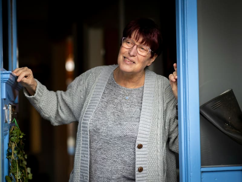 A woman opening her front door with a smile.